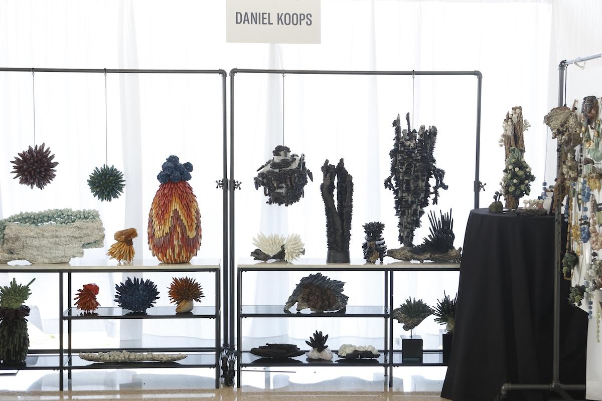 Art sculptures displayed on metal shelves in a bright room.