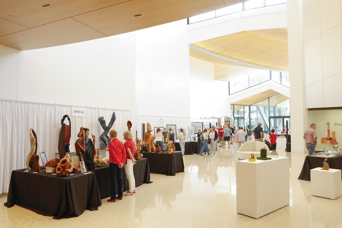 Art exhibition in a spacious gallery with sculptures and visitors.