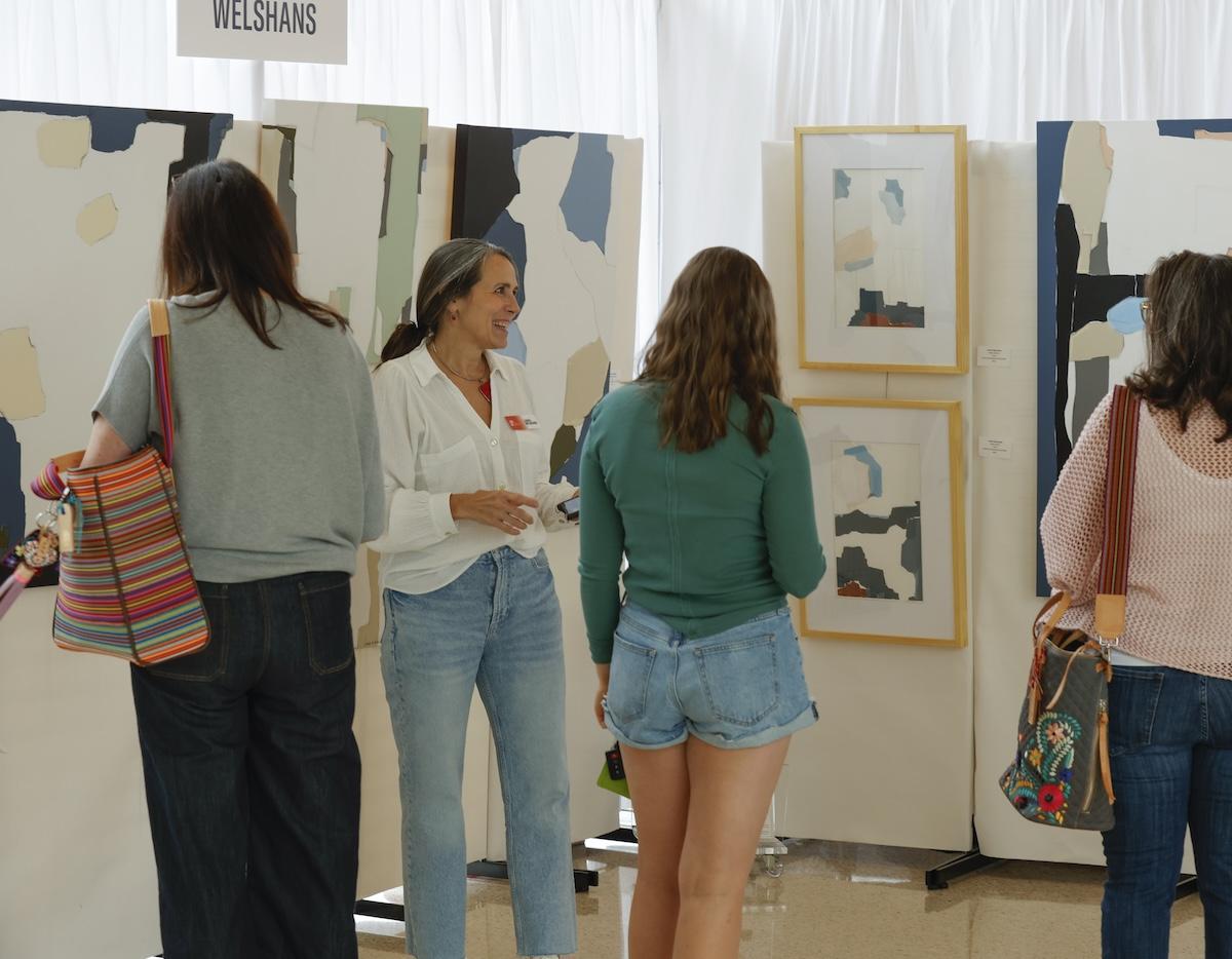 Four people viewing abstract art in a gallery setting.