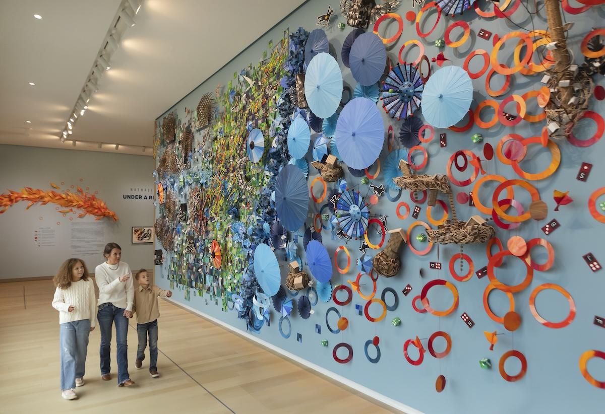 Family walking past colorful wall art in a gallery.