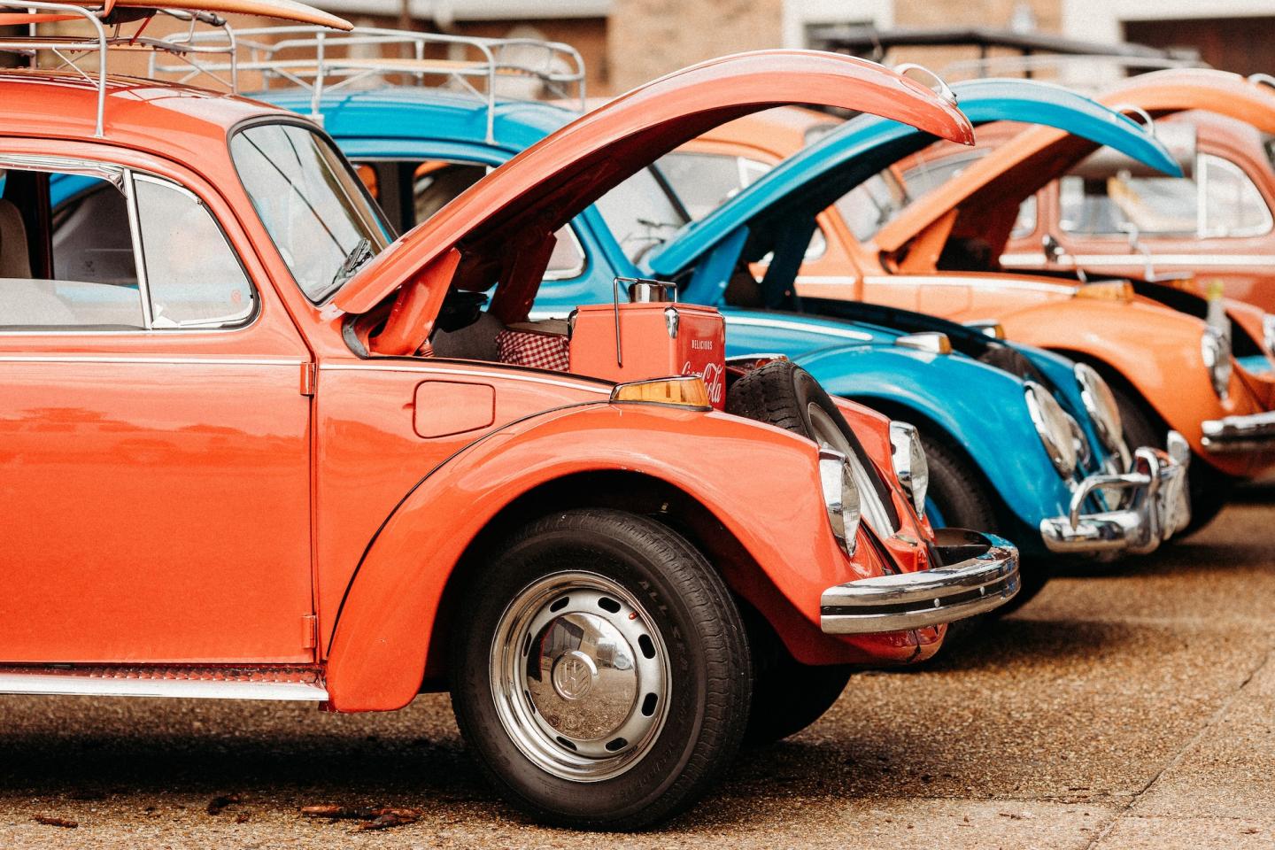 Classic cars with open hoods, parked in a row.
