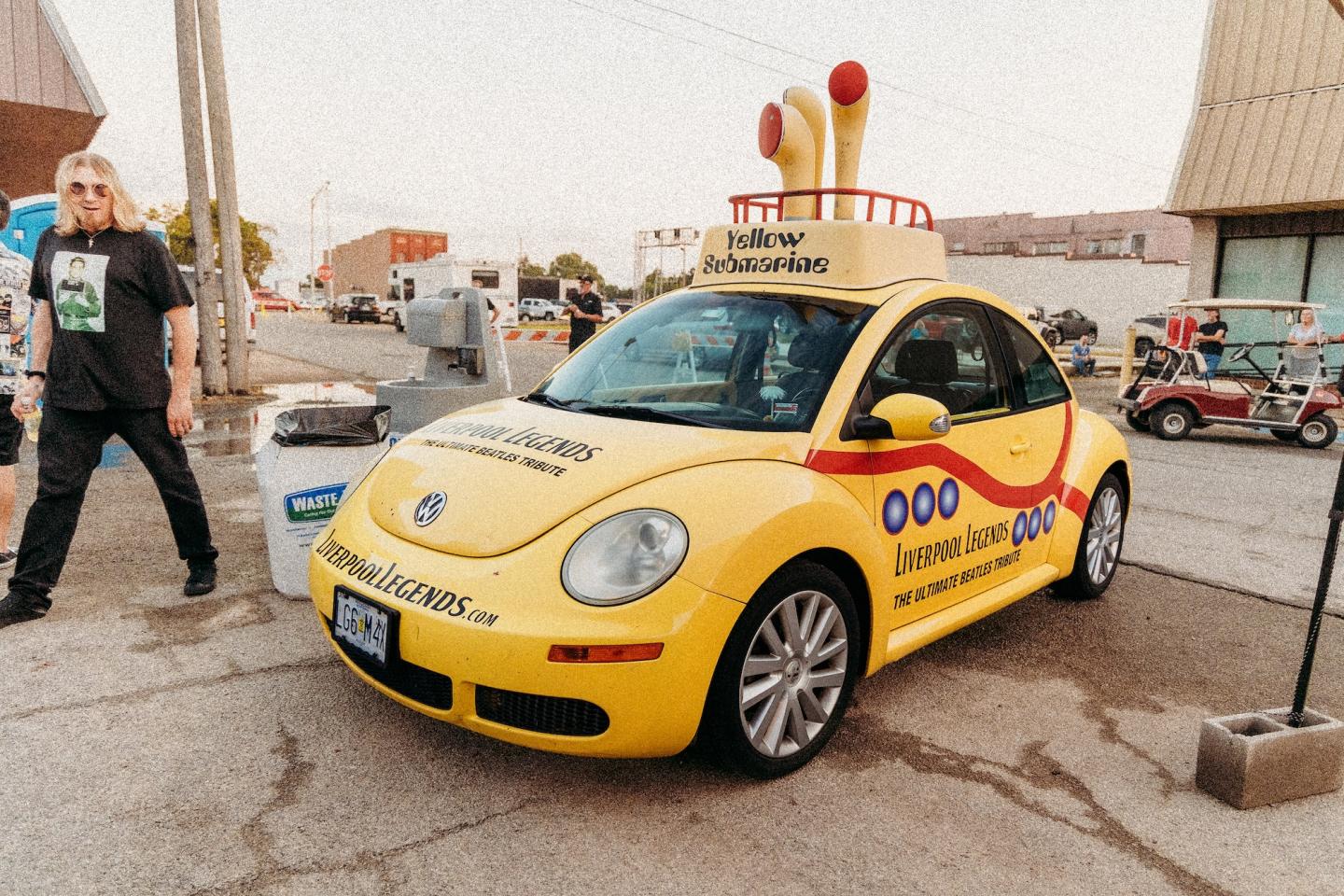 Yellow Volkswagen Beetle decorated with bowling pins on the roof.