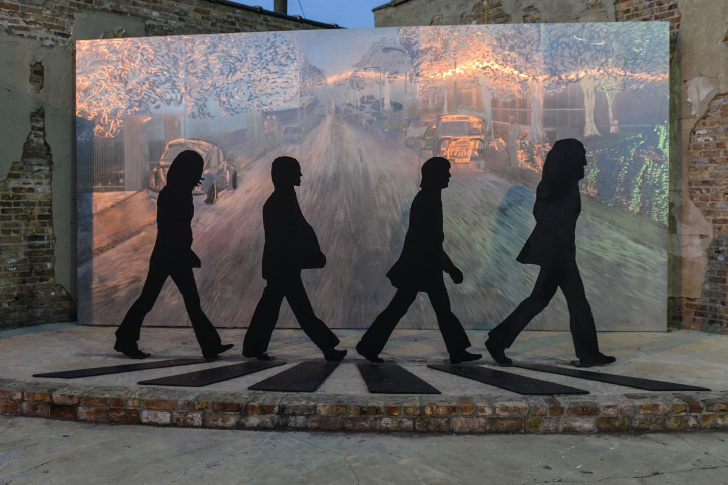 Silhouettes of four figures walking on a crosswalk mural.