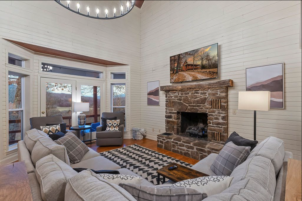 Cozy living room with stone fireplace, large gray sofa, and modern decor.