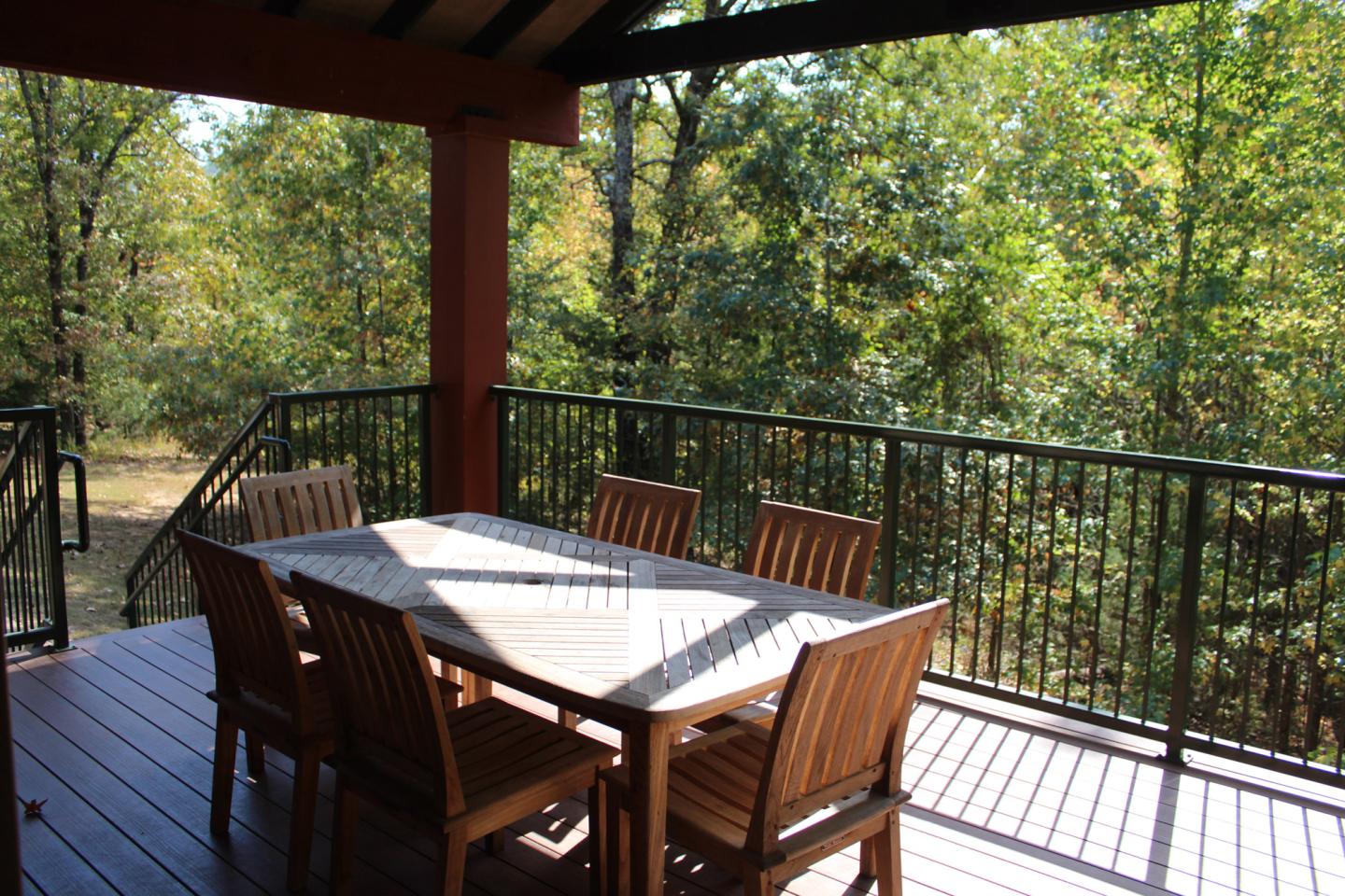 Wooden patio set on a deck with trees in the background.