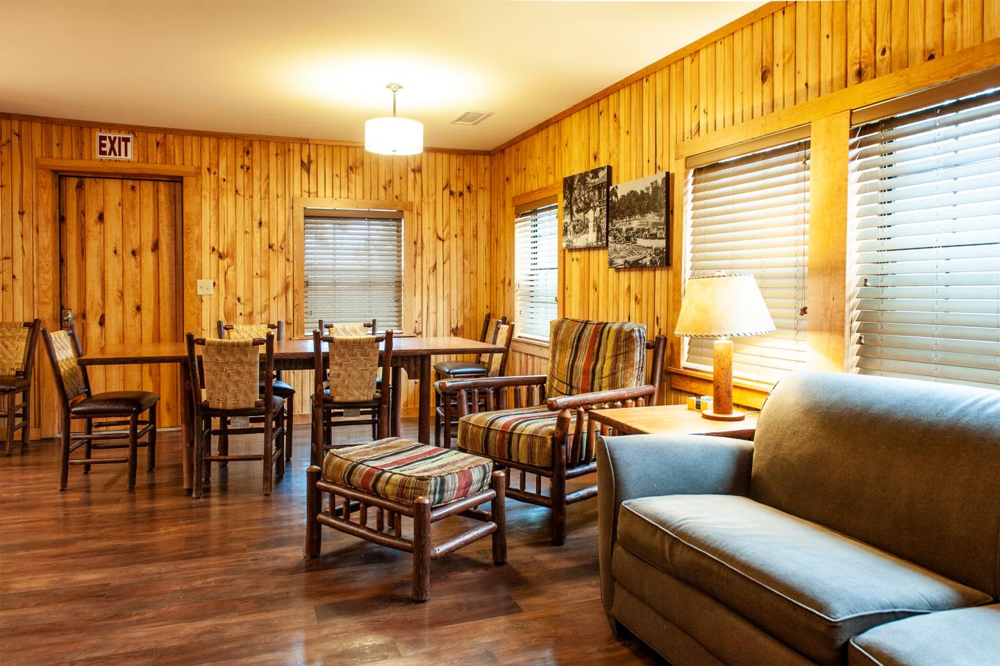Rustic cabin room with wooden walls, dining table, and cozy seating area.