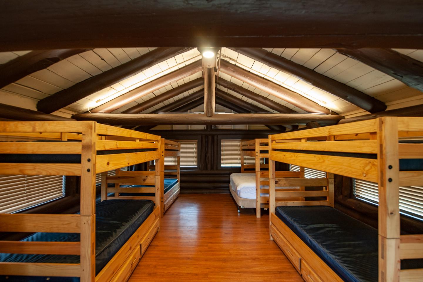 Cozy attic with wooden bunk beds and a single mattress.