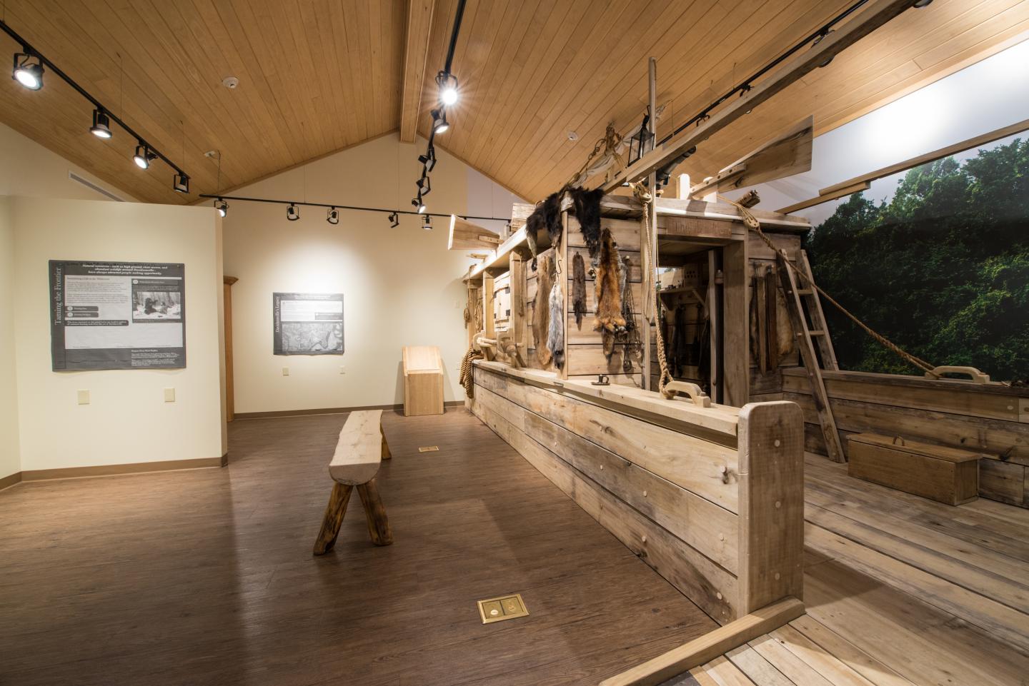 Rustic museum display of a wooden boat indoors with wooden benches.
