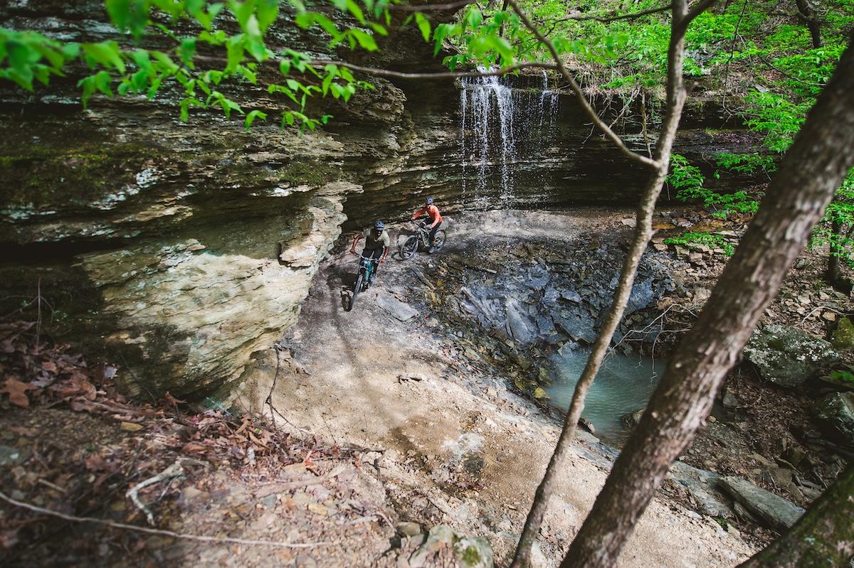 Small waterfall flowing over rocks in a lush forest setting.
