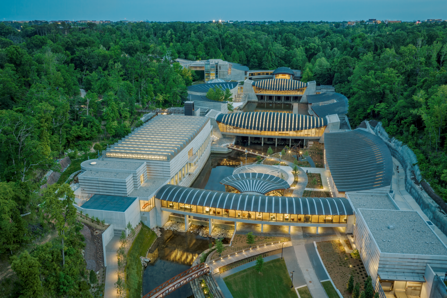 Aerial view of a modern building complex surrounded by lush green forest.
