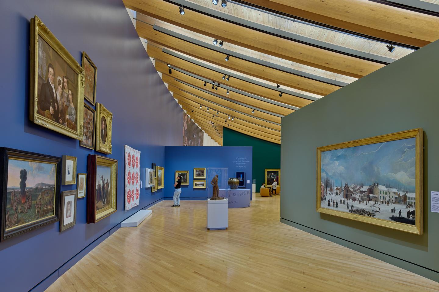 Gallery interior with colorful walls, various framed paintings, and a wooden floor.