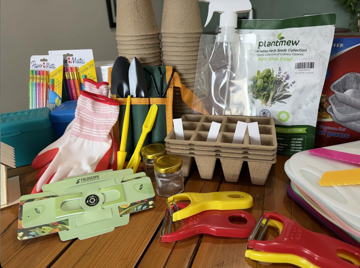 Gardening tools and supplies arranged on a table, including gloves and seed trays.