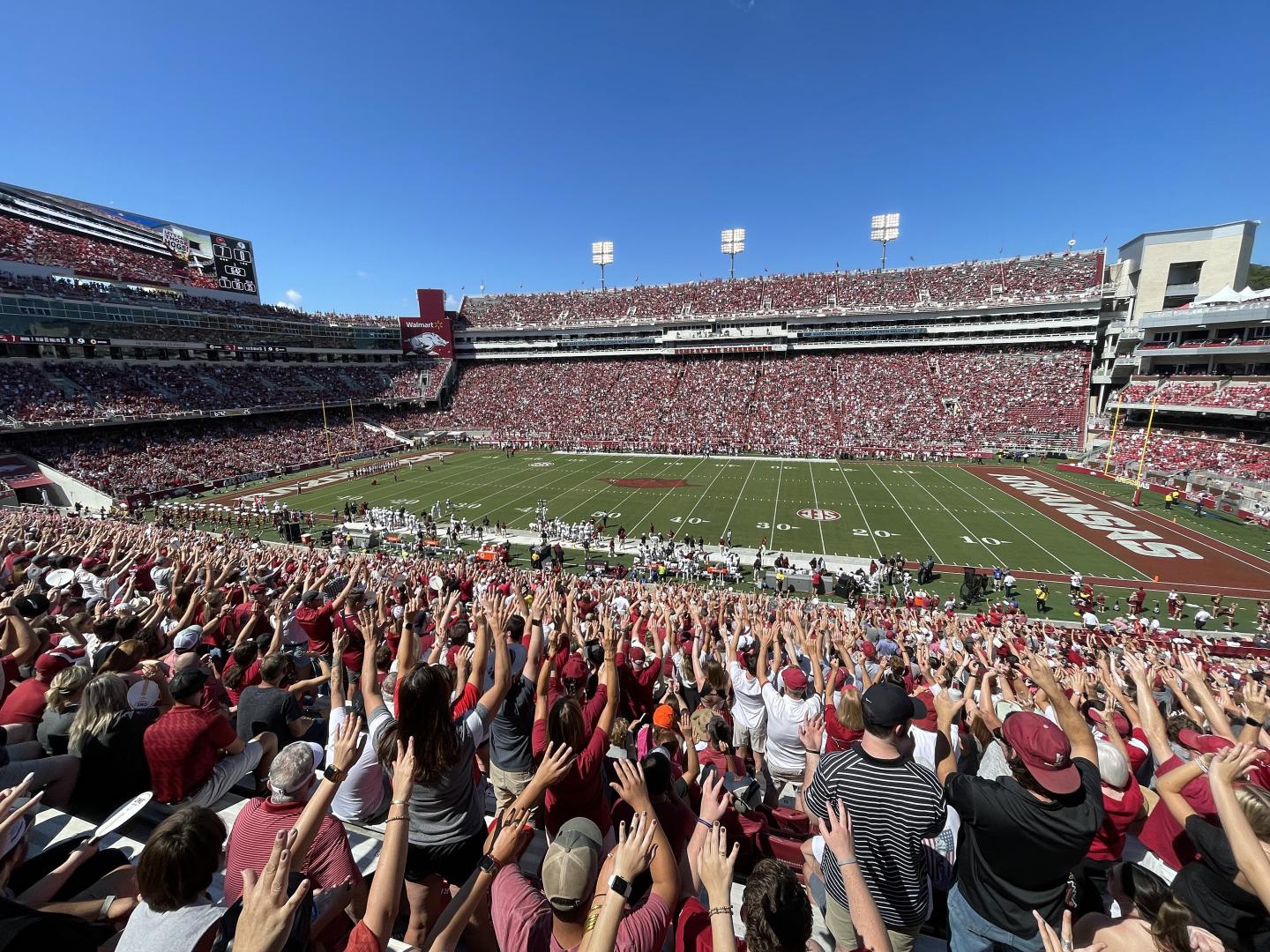 Crowd at a large football stadium under a clear blue sky.