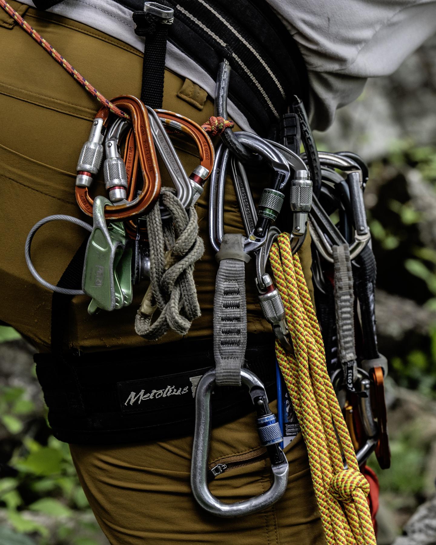 Rock climbing gear on harness with carabiners and rope.