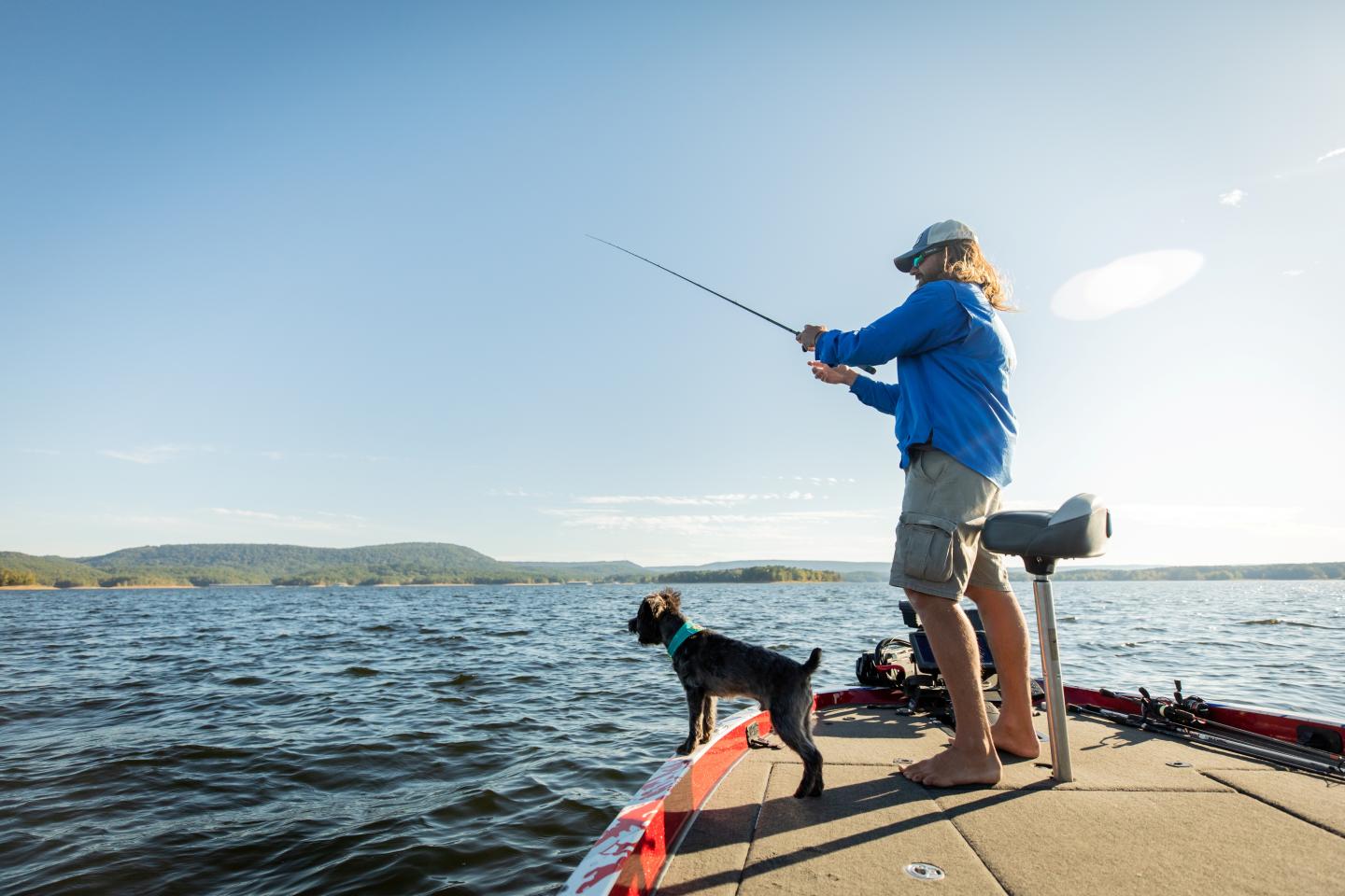 Fishing on a boat with a dog under clear blue sky.