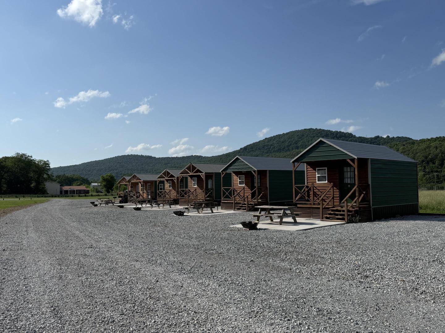 Row of small wooden cabins under construction on a gravel lot.