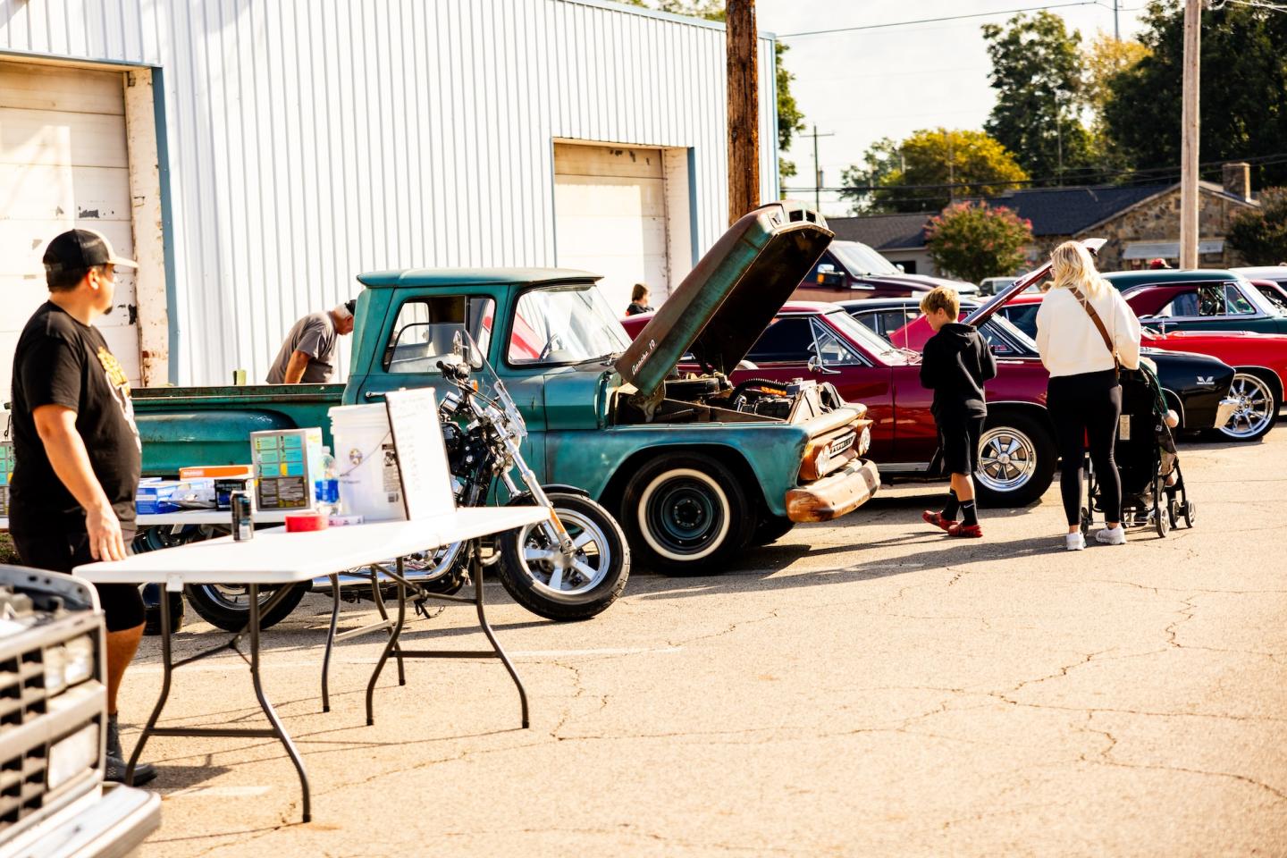 Car show with people viewing vintage vehicles outdoors.