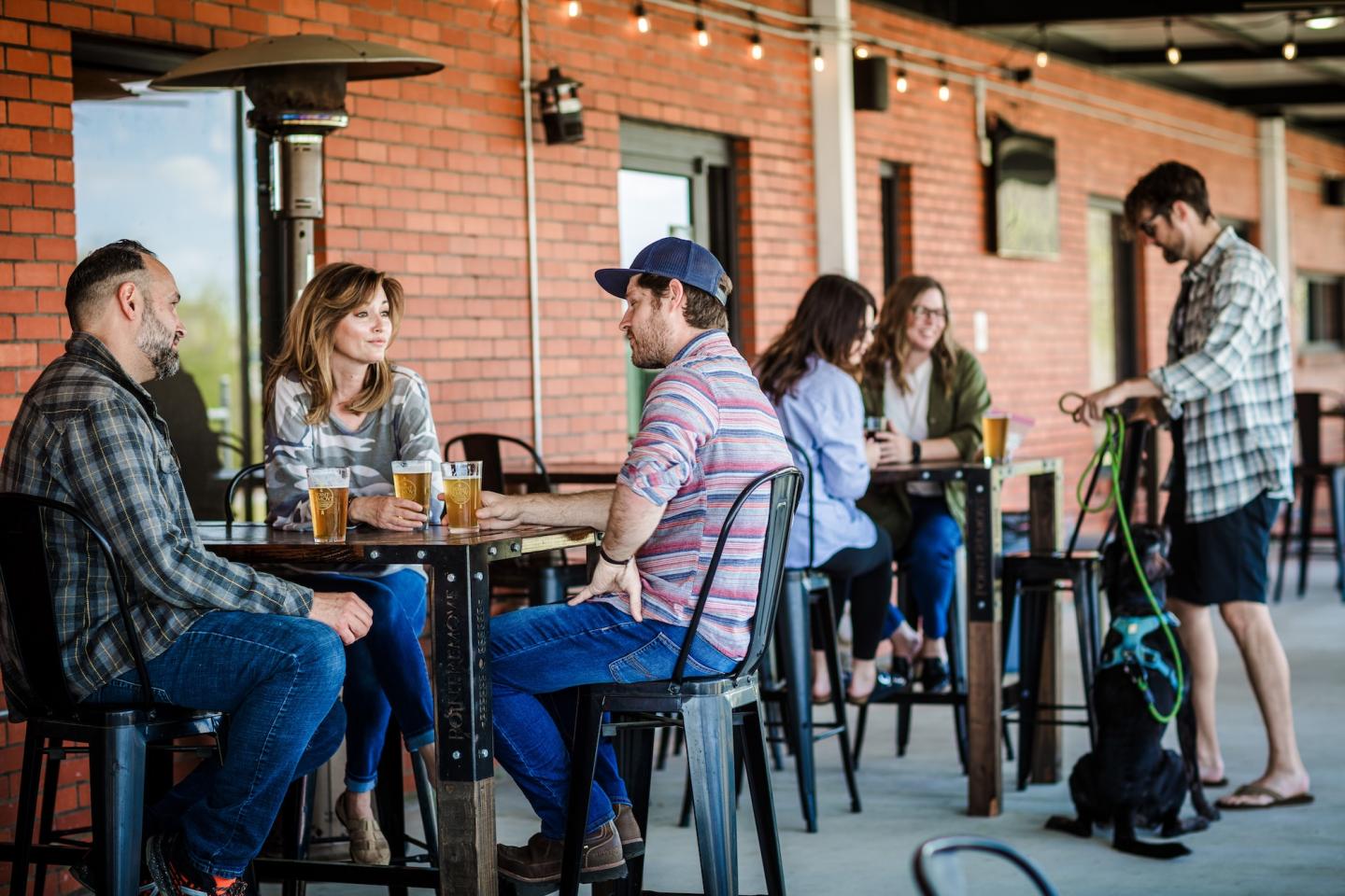 People socializing at tables in a brick-walled café.