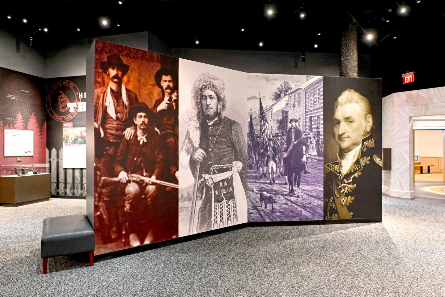 Museum exhibit panels with historical photographs and portraits in a dim gallery.
