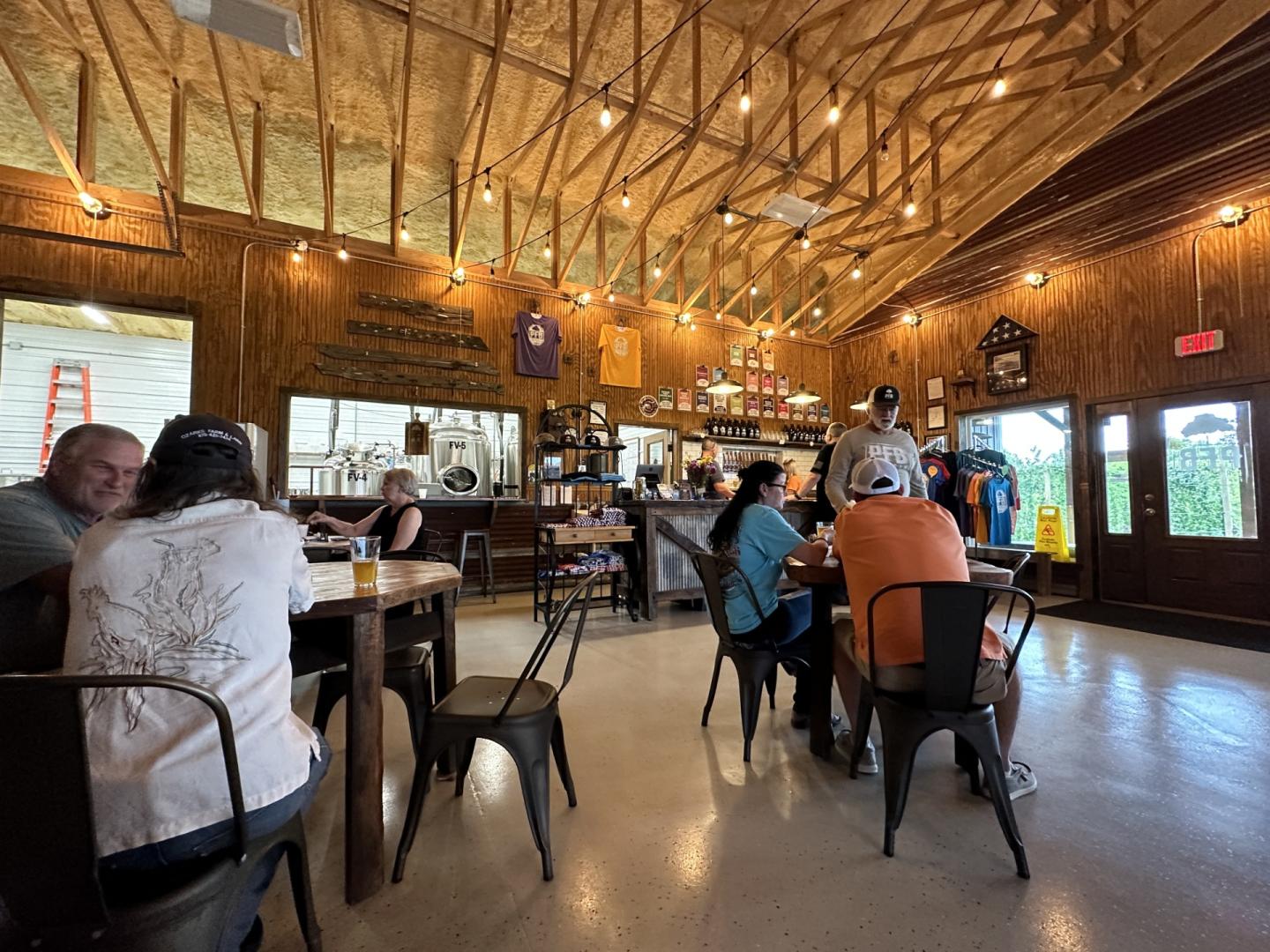 Warm, rustic café interior with patrons seated at tables beneath string lights.