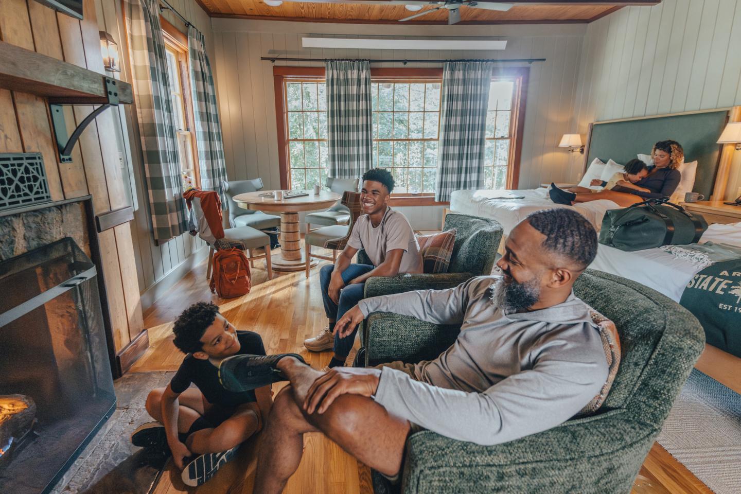 Man relaxes in an armchair while his children lounge around him in a cozy living room.