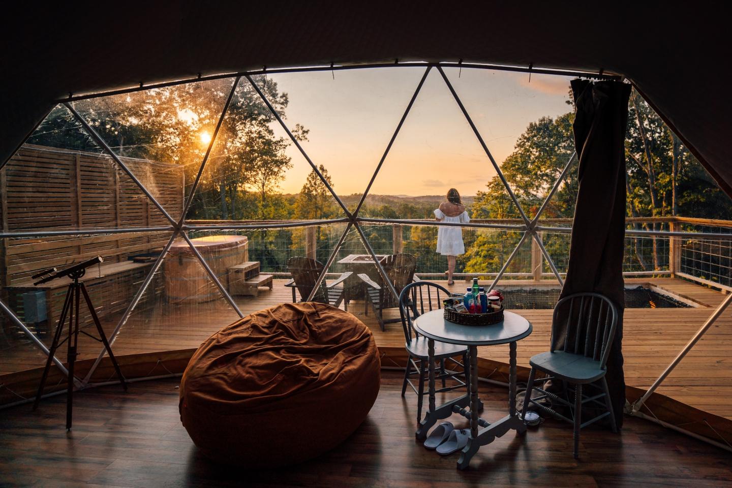 Cozy geodesic dome lounge at sunset with beanbag, tables, and city view