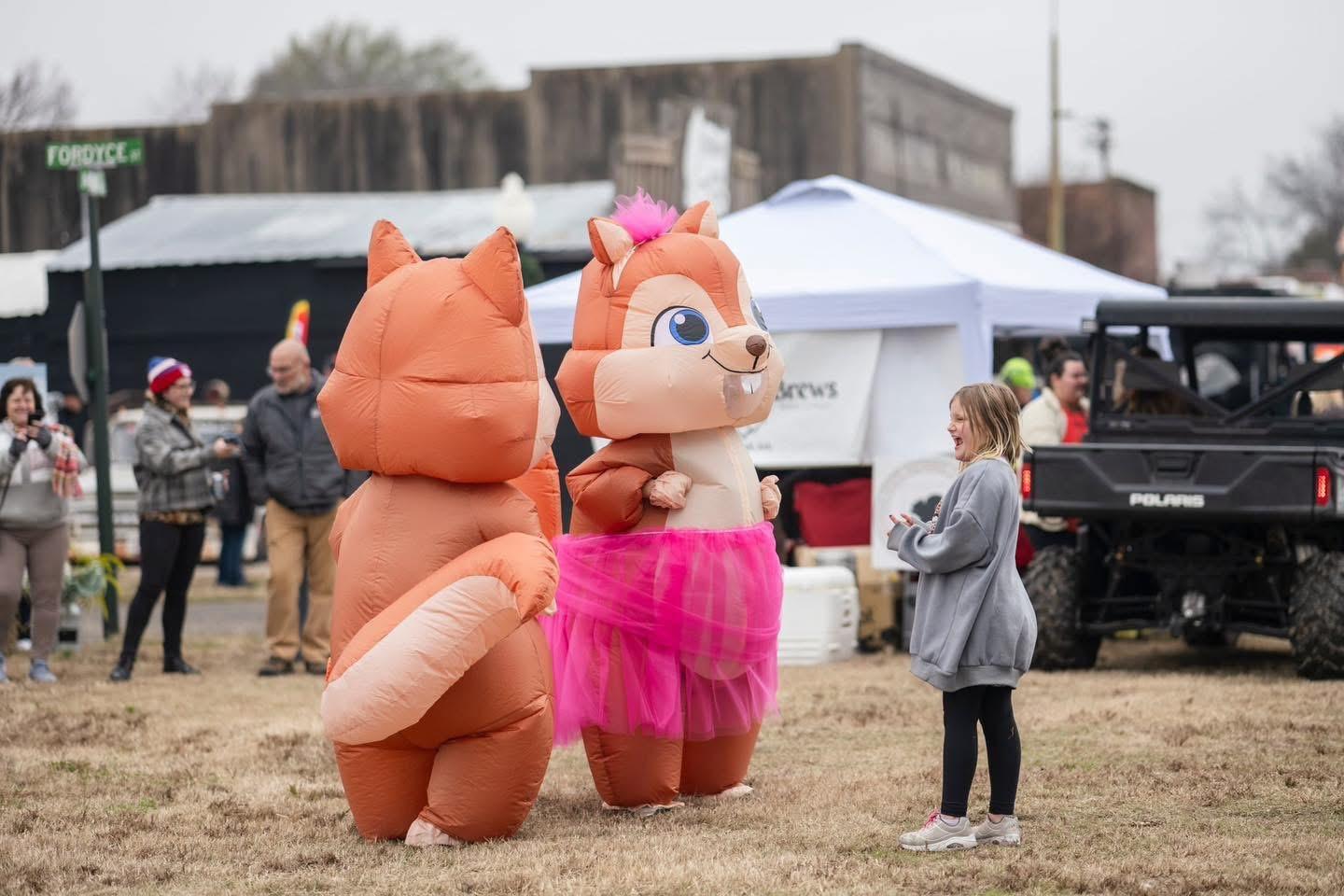 Two people in colorful animal costumes at an outdoor festival.