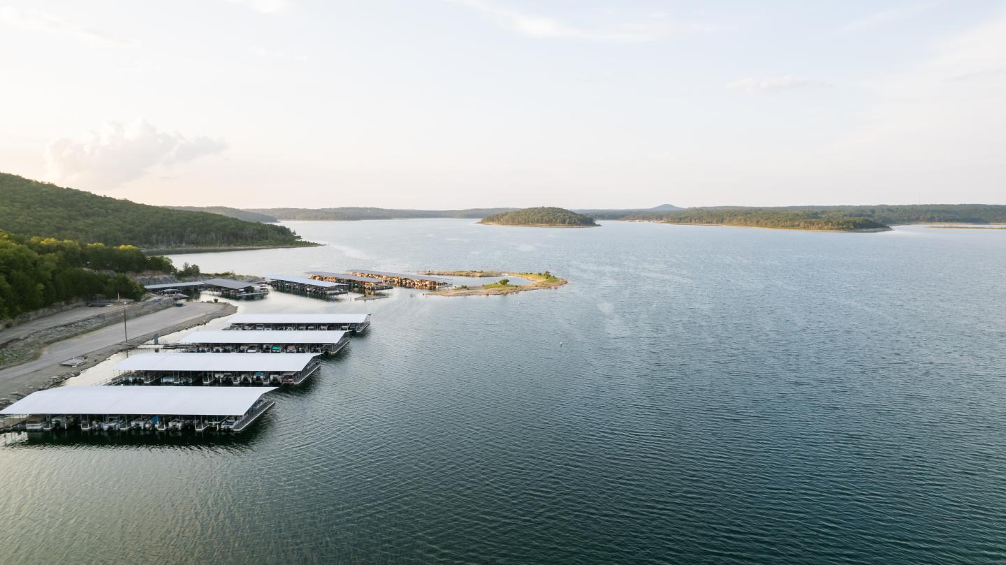 Aerial view of a calm lake with docks, boats, and forested shoreline