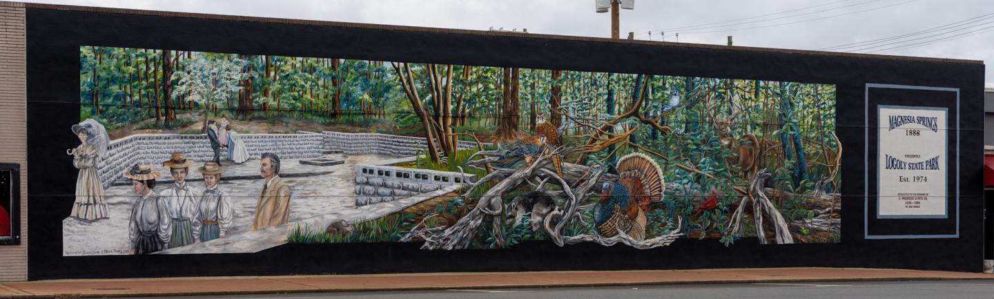 Mural of colorful vines and animals along a dark wall, with a poster on the right.