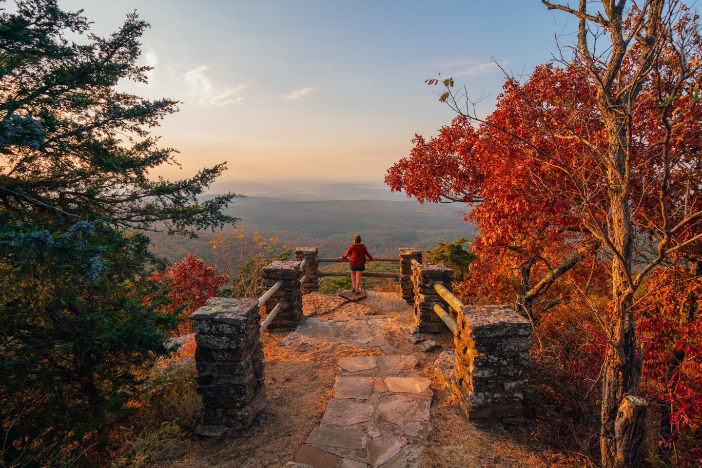 Stone path overlooking a valley at sunset, framed by autumn trees