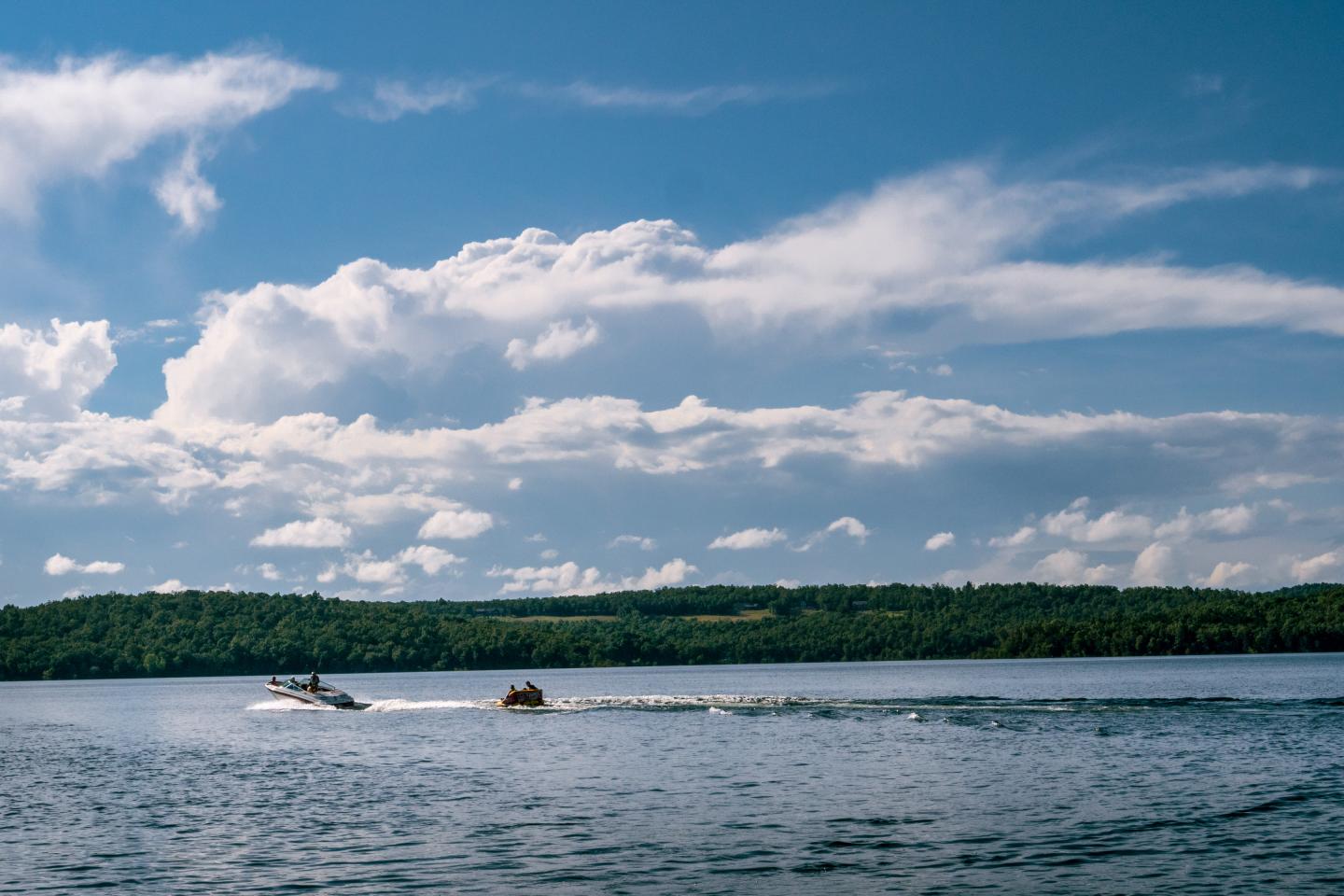 Small boats on a lake beneath dramatic clouds and a blue sky