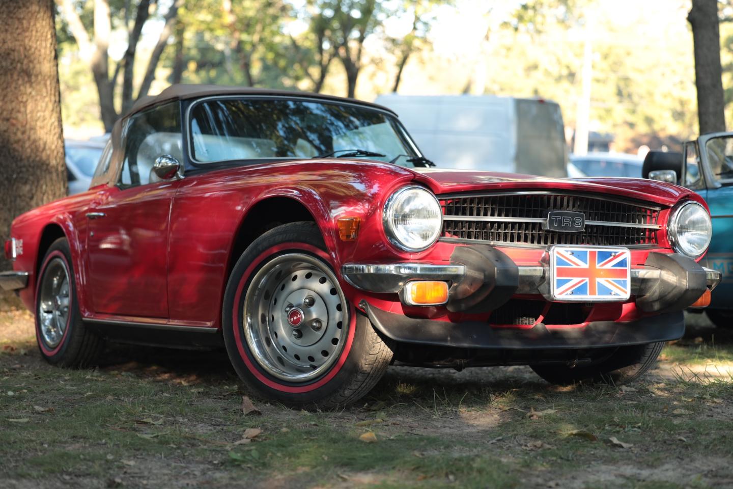 Red vintage convertible sports car with a British flag license plate.