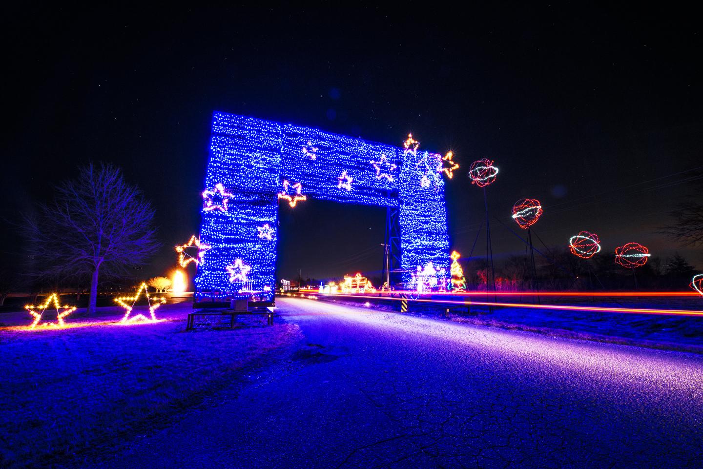 Blue illuminated archway at night with colorful light trails and star decorations