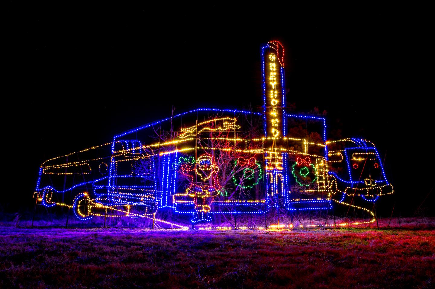 Neon-outlined camper van at night with a glowing chimney and colorful reflections