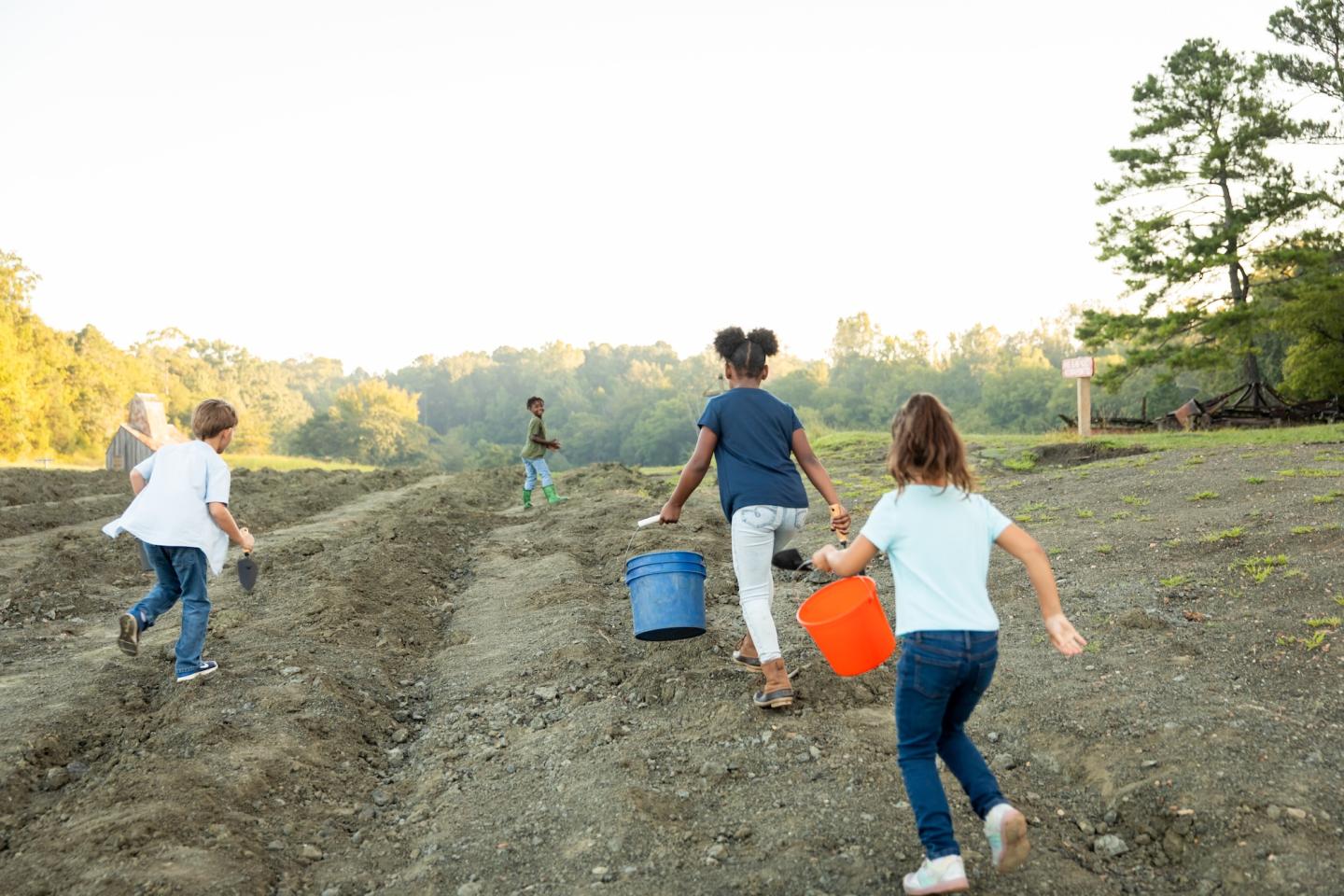 Family walking through a freshly plowed field at sunset