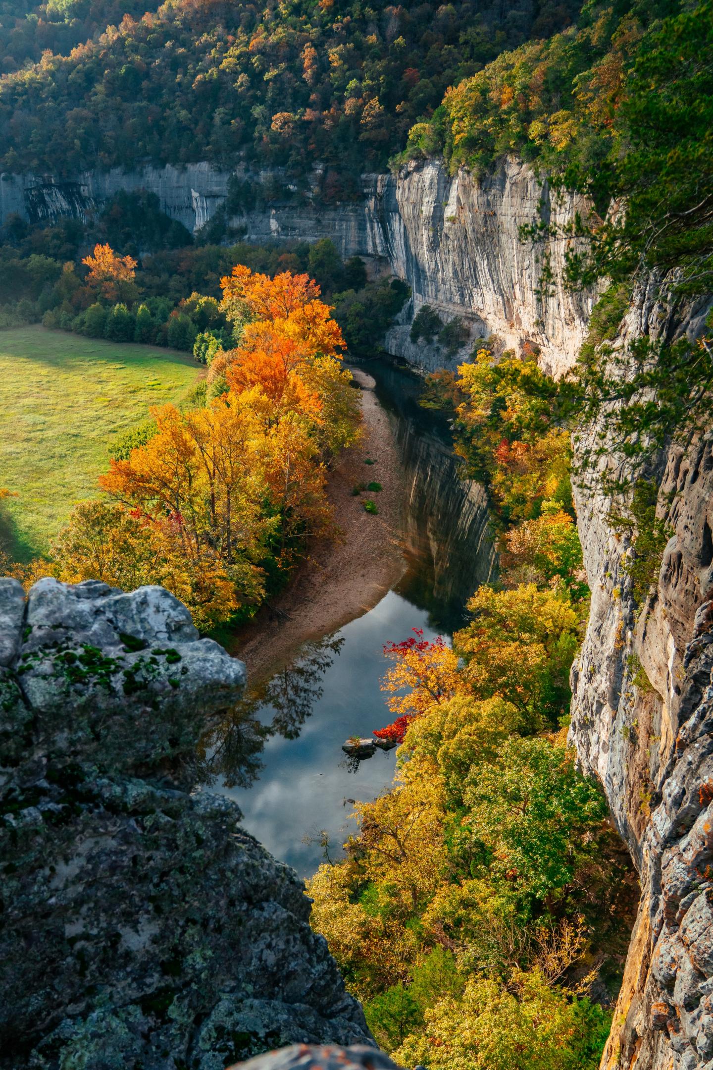 Autumn forest and winding river beneath towering limestone cliffs