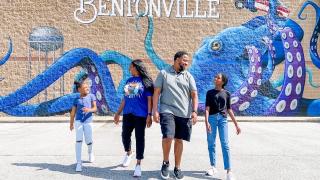 A family of four laughing in front of a mural of an Octopus 