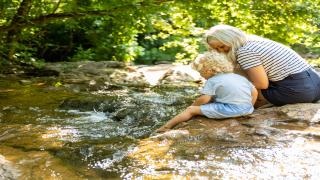 A mother an child sitting along a creek 