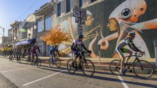 Cyclists riding by a mural