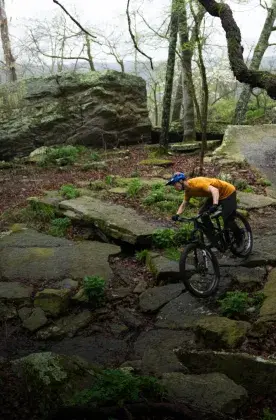 woman biker offtrail on rocks in forest
