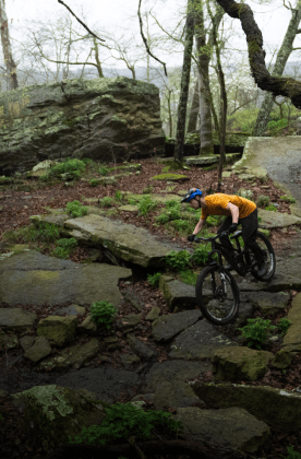 woman biker offtrail on rocks in forest