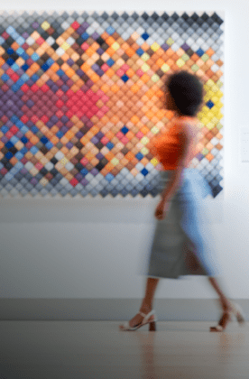 artsy photo of blurred woman walking past painting on wall